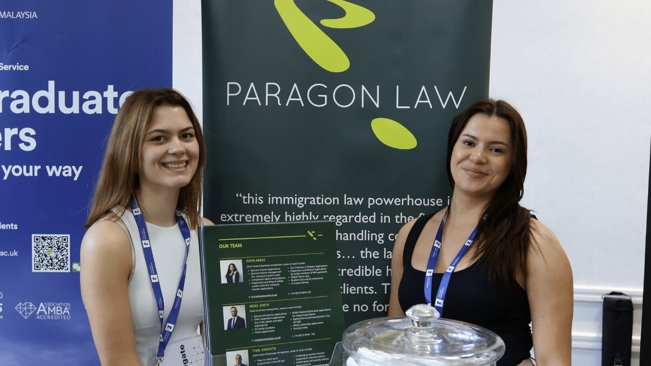 Photograph of two ladies in front of a banner which says 'Paragon Law'